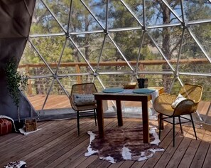 A tented outdoor area with a wooden table, two wicker chairs, and a cowhide rug. - Beautiful Dome with Fire Pit in Hermosa, South Dakota (Hermosa)
