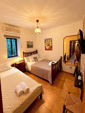 Habitación de hotel con dos camas, un espejo grande, un cuadro y vistas al exterior a través de una ventana.