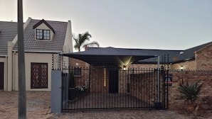 A gated residential property with a brick wall, a metal gate, and a covered driveway. - Saxon Guest Cottage Suite (Cape Town)