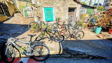 Bicicletas estacionadas frente a un rústico edificio de piedra con un persiano verde.