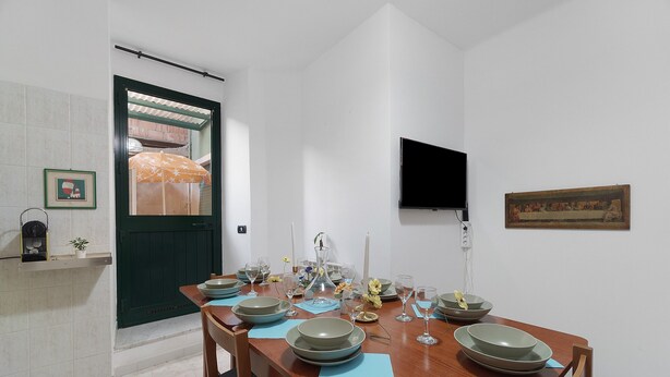 A dining area with a wooden table set for four, surrounded by chairs. - Varazze Mare Apartment with Two Bathrooms and Courtyard (Varazze)