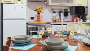 A kitchen with a dining table set for four, a stove, microwave, and cabinets. - Varazze Mare Apartment with Two Bathrooms and Courtyard (Varazze)