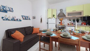 A modern living space with a sofa, dining table, and kitchen area. - Varazze Mare Apartment with Two Bathrooms and Courtyard (Varazze)