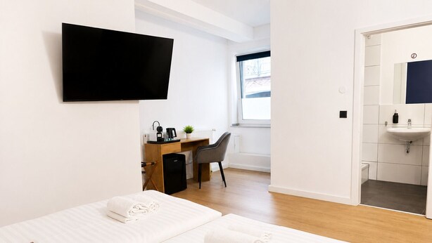 Habitación de hotel con dos camas, un escritorio con computadora, un televisor y un baño con lavamanos.