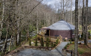 A yurt with a wooden deck and a gravel path leading to it, surrounded by trees. - Heavenly Yurt with Modern Interior in Topton, North Carolina (Topton)