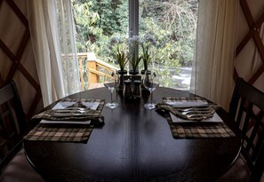 A dining table set for two with a view of greenery outside. - Heavenly Yurt with Modern Interior in Topton, North Carolina (Topton)