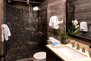 A modern bathroom with a glass-enclosed shower, a marble sink, and a large mirror.