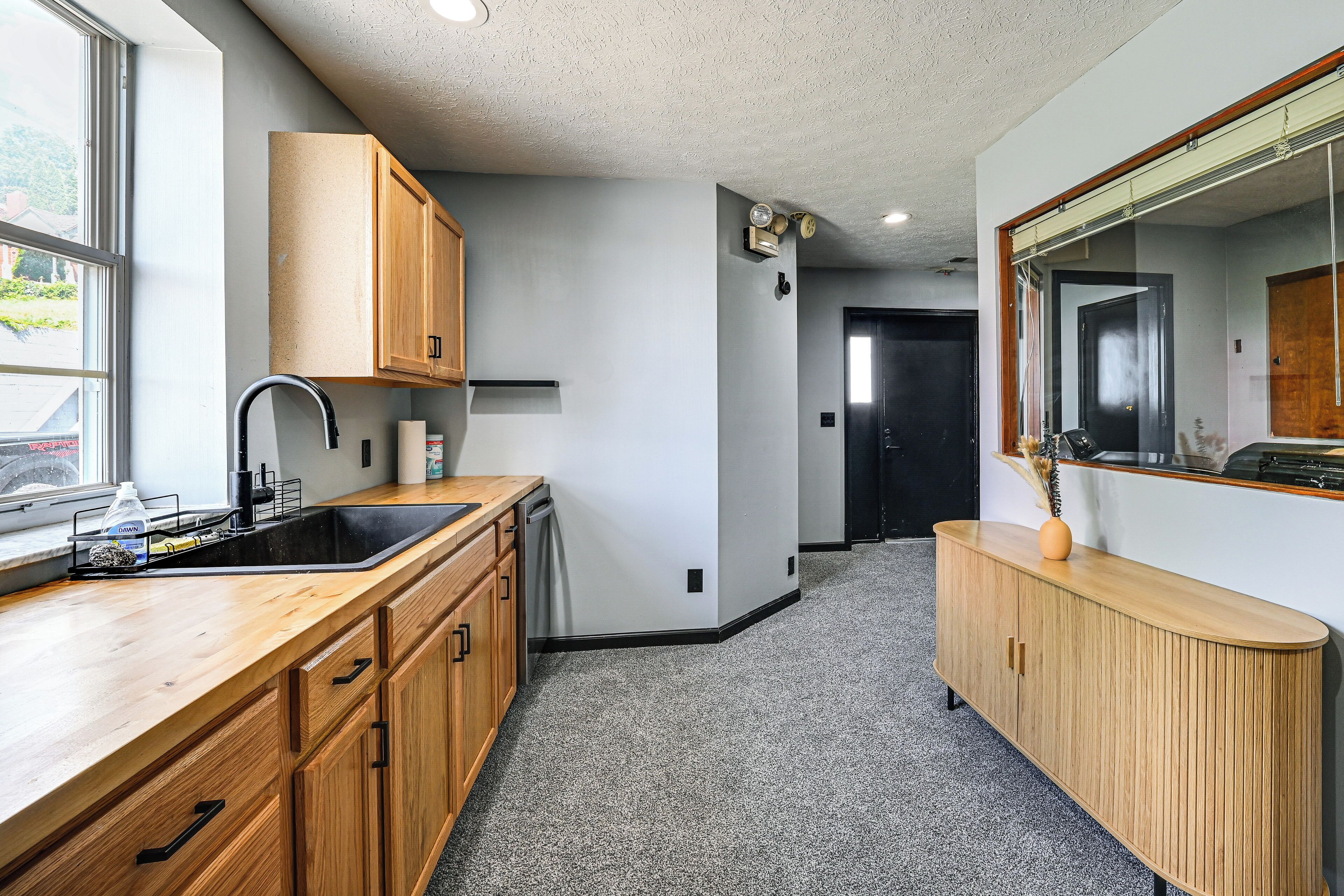 A kitchen with wooden cabinets, a black sink, and a countertop.