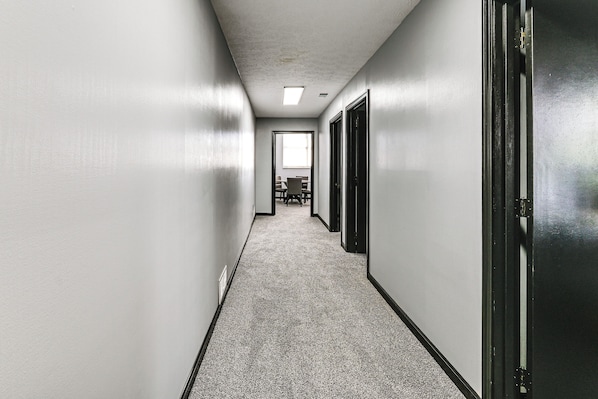 A hallway with a carpeted floor, white walls, and a door on the right.