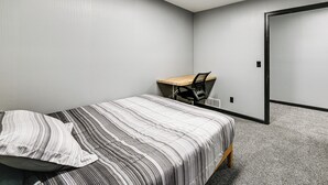 A bedroom with a bed, a desk, and a chair.