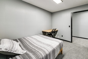A bedroom with a bed, a desk, and a chair.
