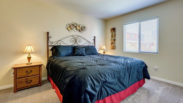 A bedroom with a bed, nightstand, wall decor, and a window. - Golf & Gamble! Mesquite Condo w/ Pool Access (Mesquite)