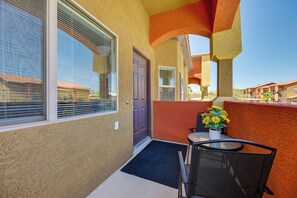 Ein Balkon mit einer Tür, einem Tisch, einem Stuhl und einem Blumentopf.