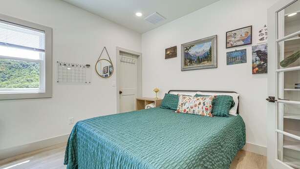 A bedroom with a bed, a window with blinds, a calendar, and wall art. - Deck & Fire Pit! Mtn Escape, 12 Mi to Asheville (Leicester)