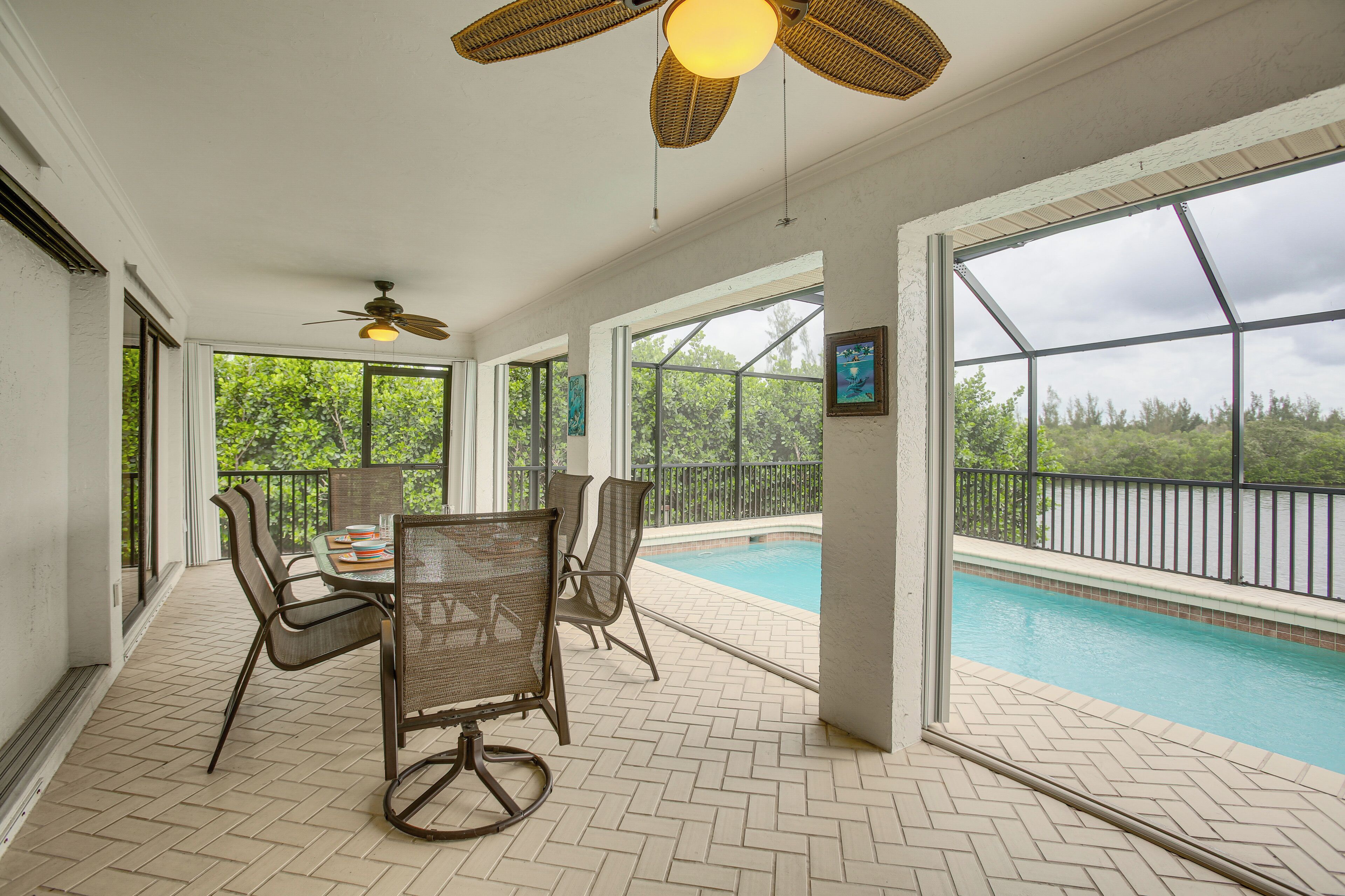 An indoor patio with a pool, ceiling fans, and a table with chairs.