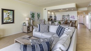A living room with a sofa, coffee table, and a dining area with chairs and a table. - 3BR Beachfront PH Suite: Suntide III - Unit 1203 (South Padre Island)