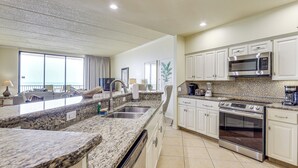 A modern kitchen with granite countertops, stainless steel appliances, and a view of the ocean. - 3BR Beachfront PH Suite: Suntide III - Unit 1203 (South Padre Island)