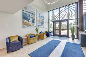 Eine Lobby mit einem blauen Sofa, einem gelben Sofa, einem kleinen Tisch und einem großen abstrakten Gemälde an der Wand.