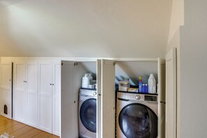 A laundry room with two washing machines, a drying rack, and various cleaning supplies.