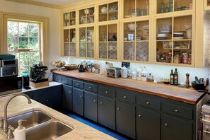 A kitchen with dark cabinets, a wooden countertop, and a window with a view of greenery.