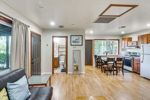 Eine moderne Küche mit Holzschränken, ein Essbereich mit Stühlen und ein Wohnzimmer mit Ledersofa.
