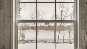 Una ventana con un letrero que dice 'EXIT', vista de un paisaje nevado y una pared de madera.