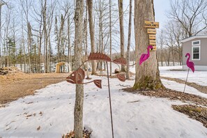 A snowy landscape with a tree, a metal fish sculpture, and a house. - Lakefront Tiny Home w/ Dock Near Chetek! (Bruce)