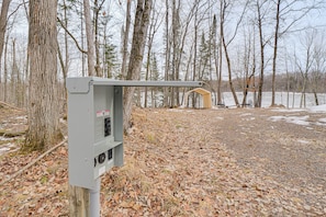 A utility box with a metal arm and a wooden structure in a wooded area. - Lakefront Tiny Home w/ Dock Near Chetek! (Bruce)