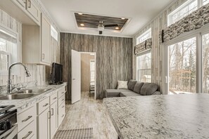 A modern kitchen with marble countertops, a built-in oven, and a ceiling fan. - Lakefront Tiny Home w/ Dock Near Chetek! (Bruce)