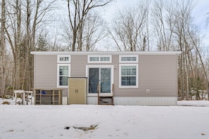 A two-story house with a garage, a front door, and a small porch. - Lakefront Tiny Home w/ Dock Near Chetek! (Bruce)