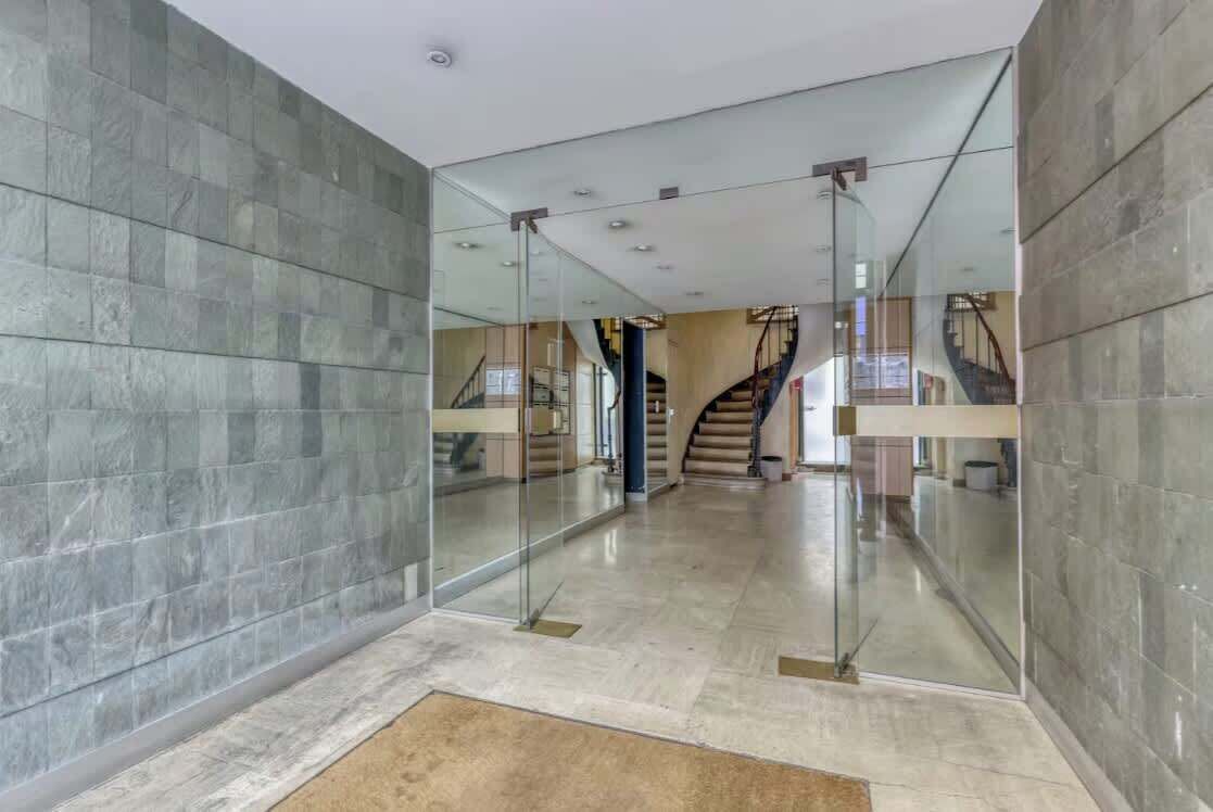 A modern interior with a glass partition, a staircase, and a tiled floor.