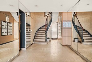 A modern interior with a curved staircase, a reception area with mailboxes, and a hallway with a glass partition. - Bright & Peaceful 2BR in Paris 10th (Paris)