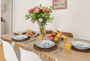 Ein Esstisch ist gedeckt mit Tellern, Gläsern und einer Obstschale. Im Hintergrund steht ein Blumenstrauß und ein Schild mit der Aufschrift Französischer Markt.
