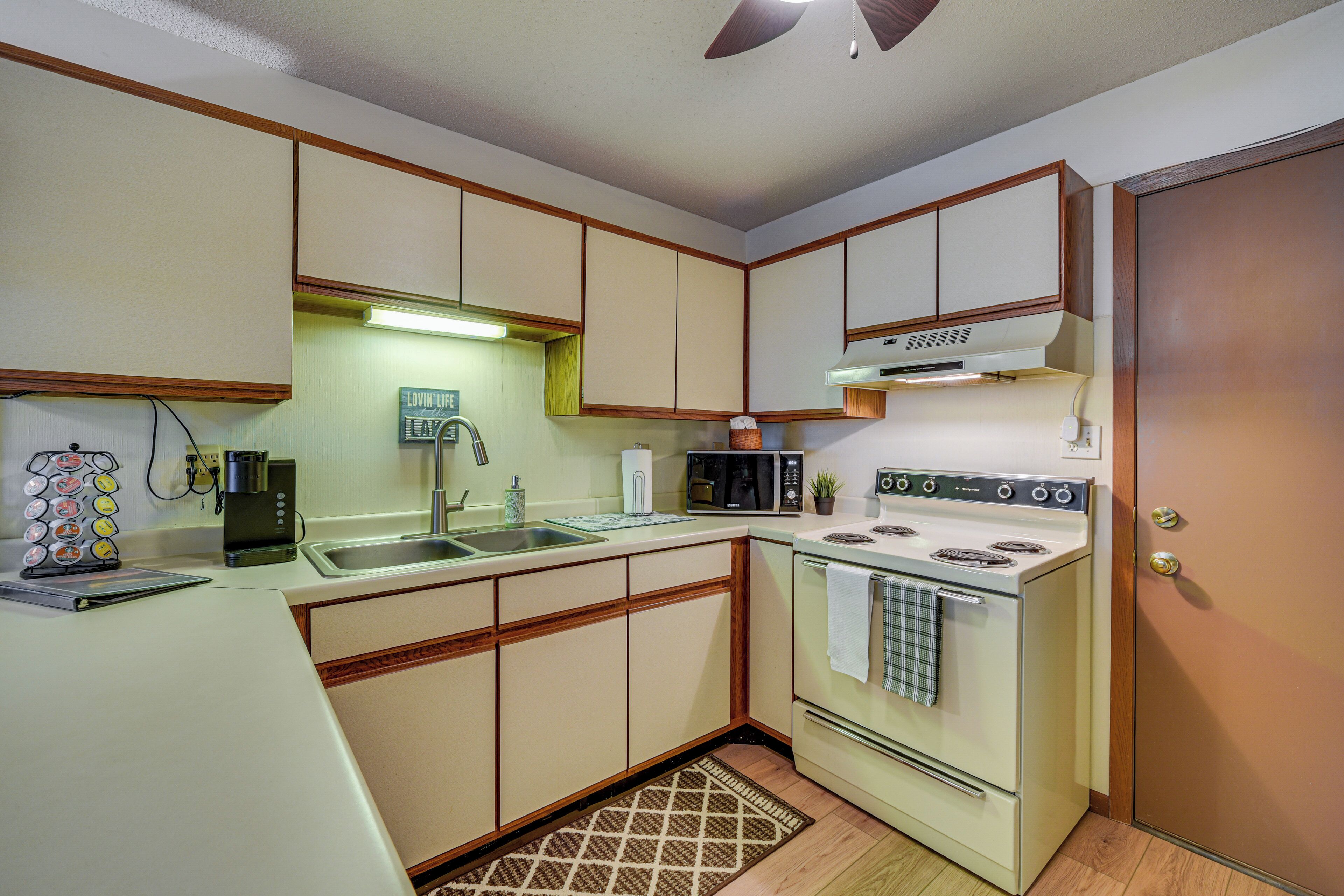 Cocina compacta con estufa, microondas, fregadero y armarios de madera.