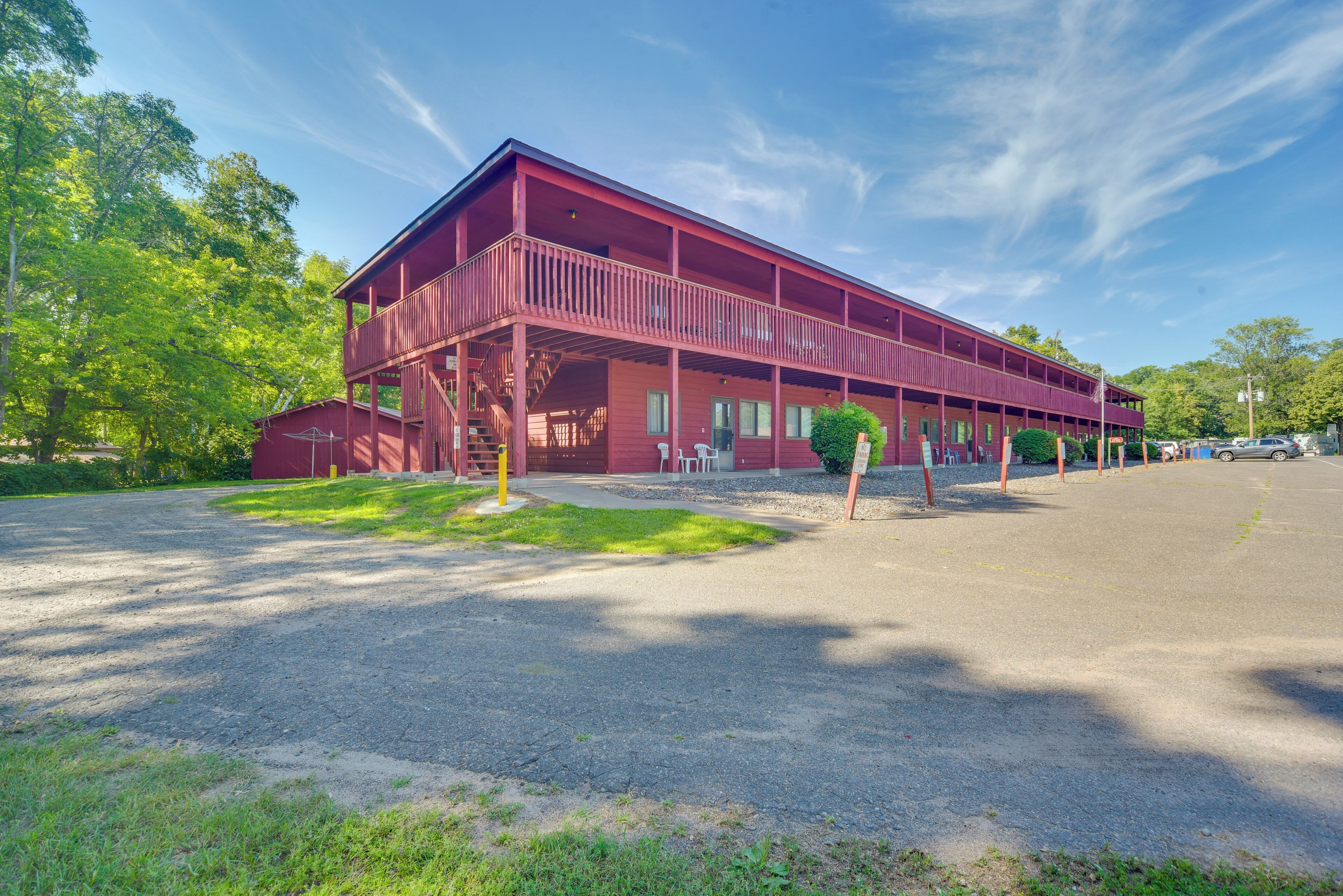 A two-story building with a red exterior, a covered porch, and a gravel driveway.