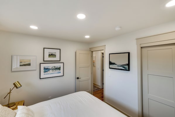A bedroom with a bed, a nightstand, a lamp, and framed pictures on the wall.