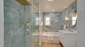 A modern bathroom with a glass shower enclosure, a freestanding bathtub, and a vanity with a mirror. - Easy NYC Commute! Home 1 Mi to Dtwn Westbury (Westbury)