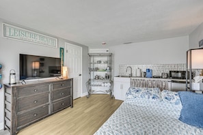 A bedroom with a bed, dresser, TV, kitchenette, and a sign reading 'Leisure Beach'. - Boat Dock Access! Pet-friendly Studio in Hudson (Hudson)