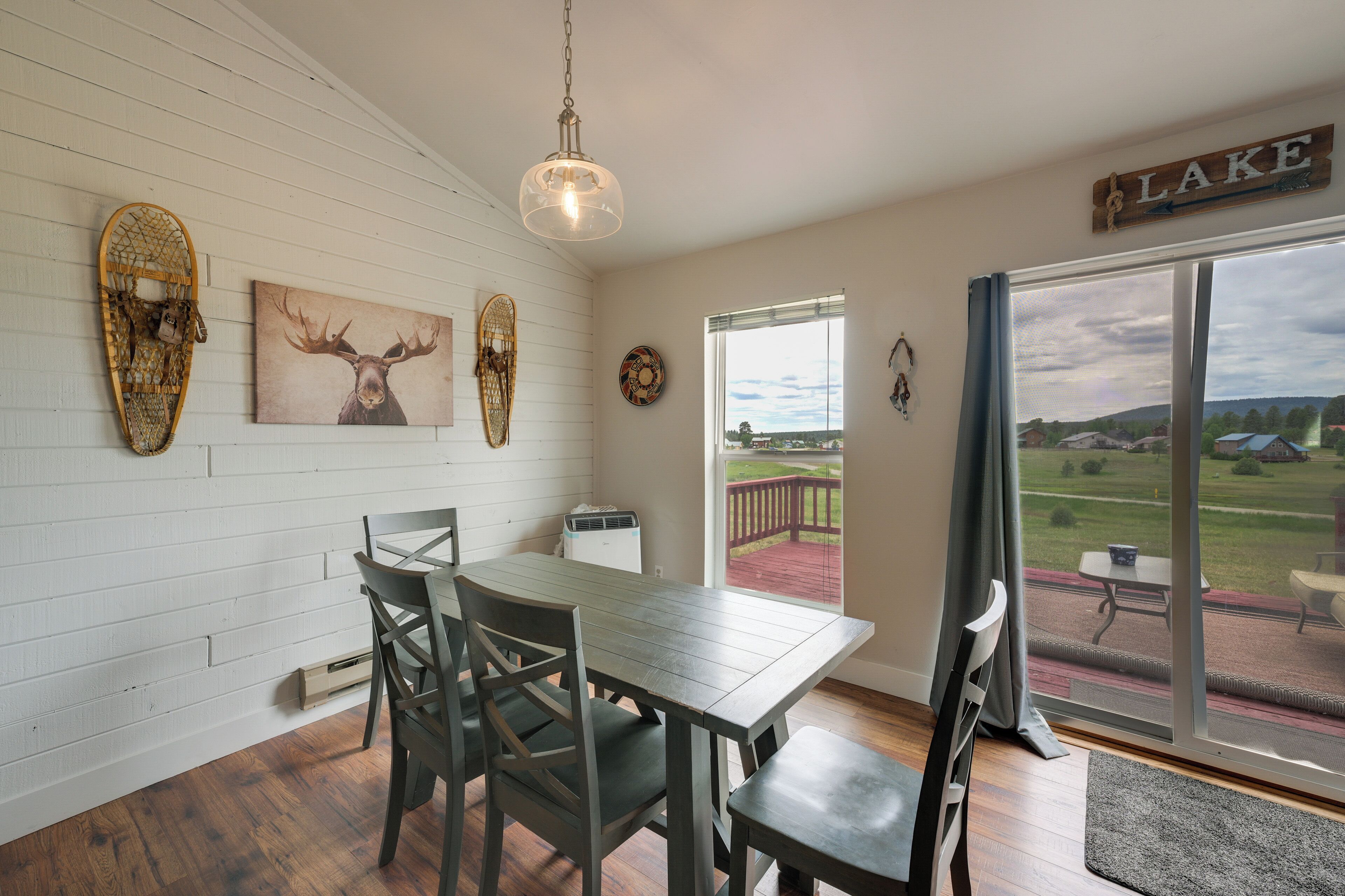 Un coin repas avec une table et des chaises, un luminaire au plafond et une vue sur une terrasse extérieure.