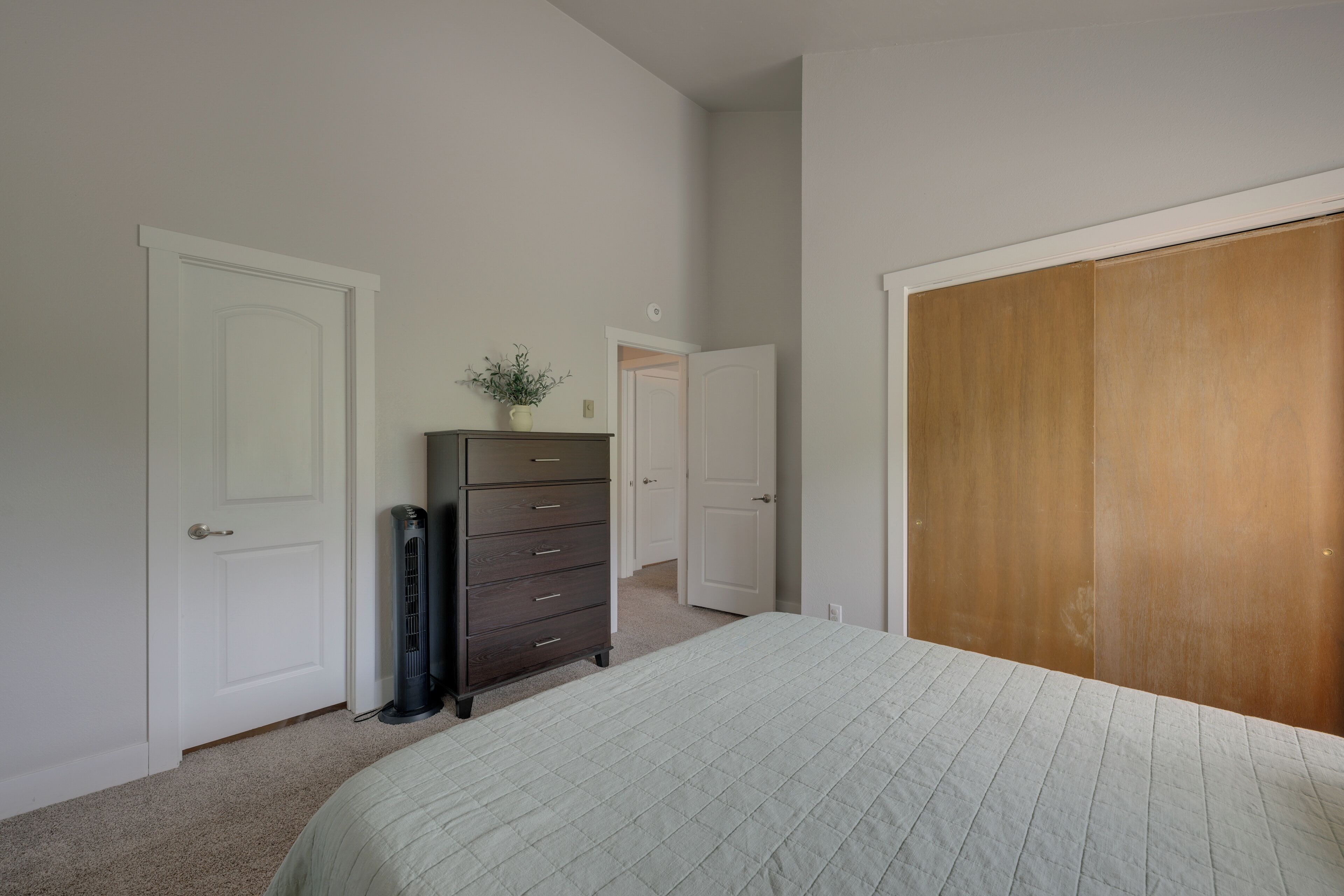 Un dormitorio con cama, cómoda, armario y puerta que da a otra habitación.