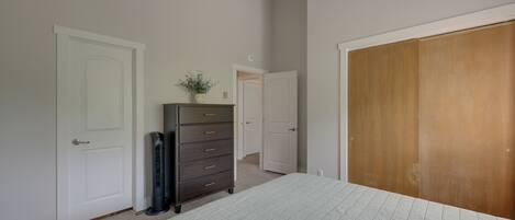 Un dormitorio con cama, cómoda, armario y puerta que da a otra habitación.