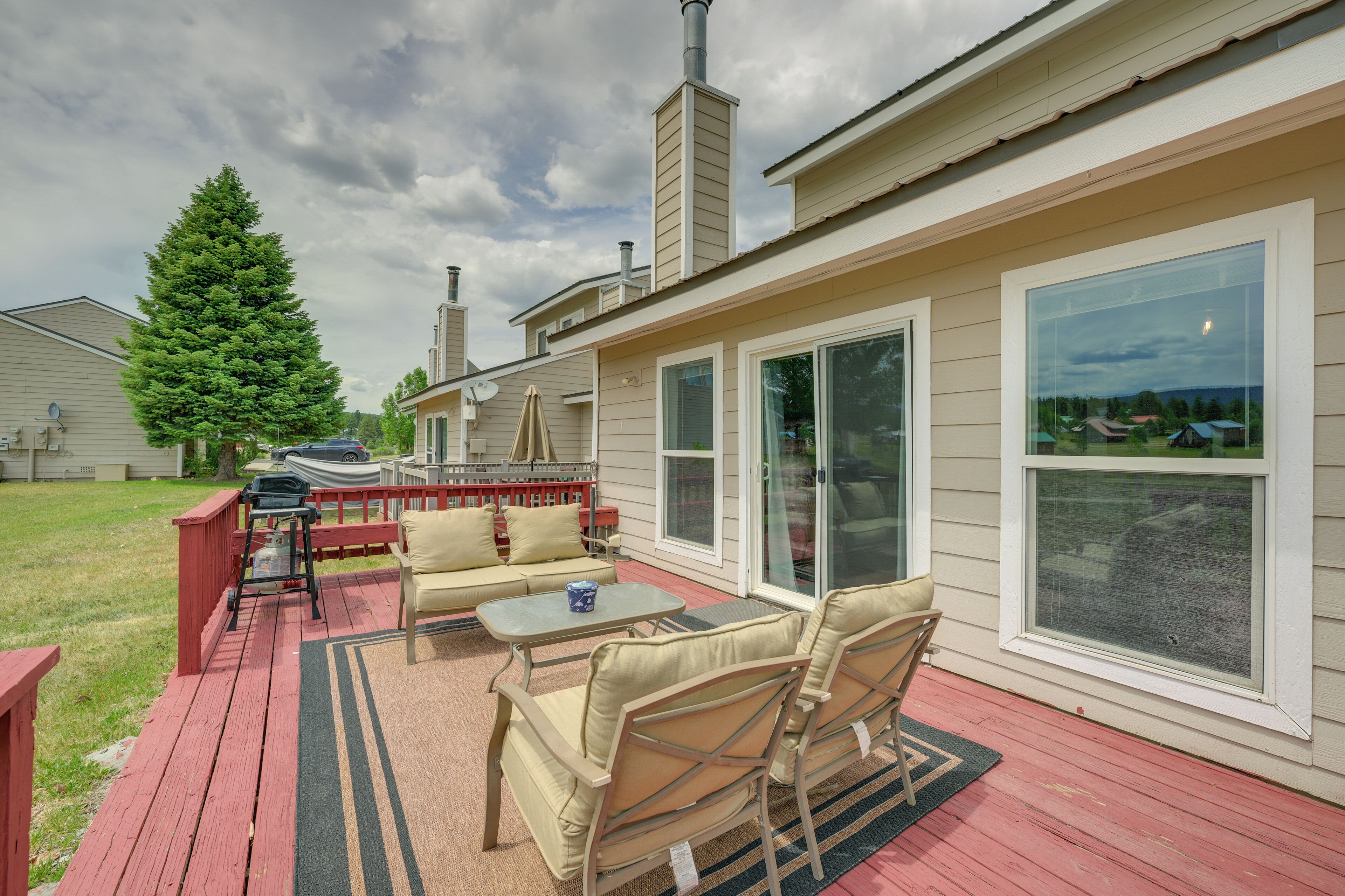 Une terrasse couverte, aménagée avec du mobilier d’extérieur, une grande fenêtre et une cheminée.