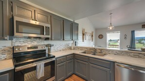A modern kitchen with stainless steel appliances, grey cabinetry, a large island with a sink, and a view of the outdoors. - Lake + Mountain Views! Pagosa Springs Getaway (Pagosa Springs)