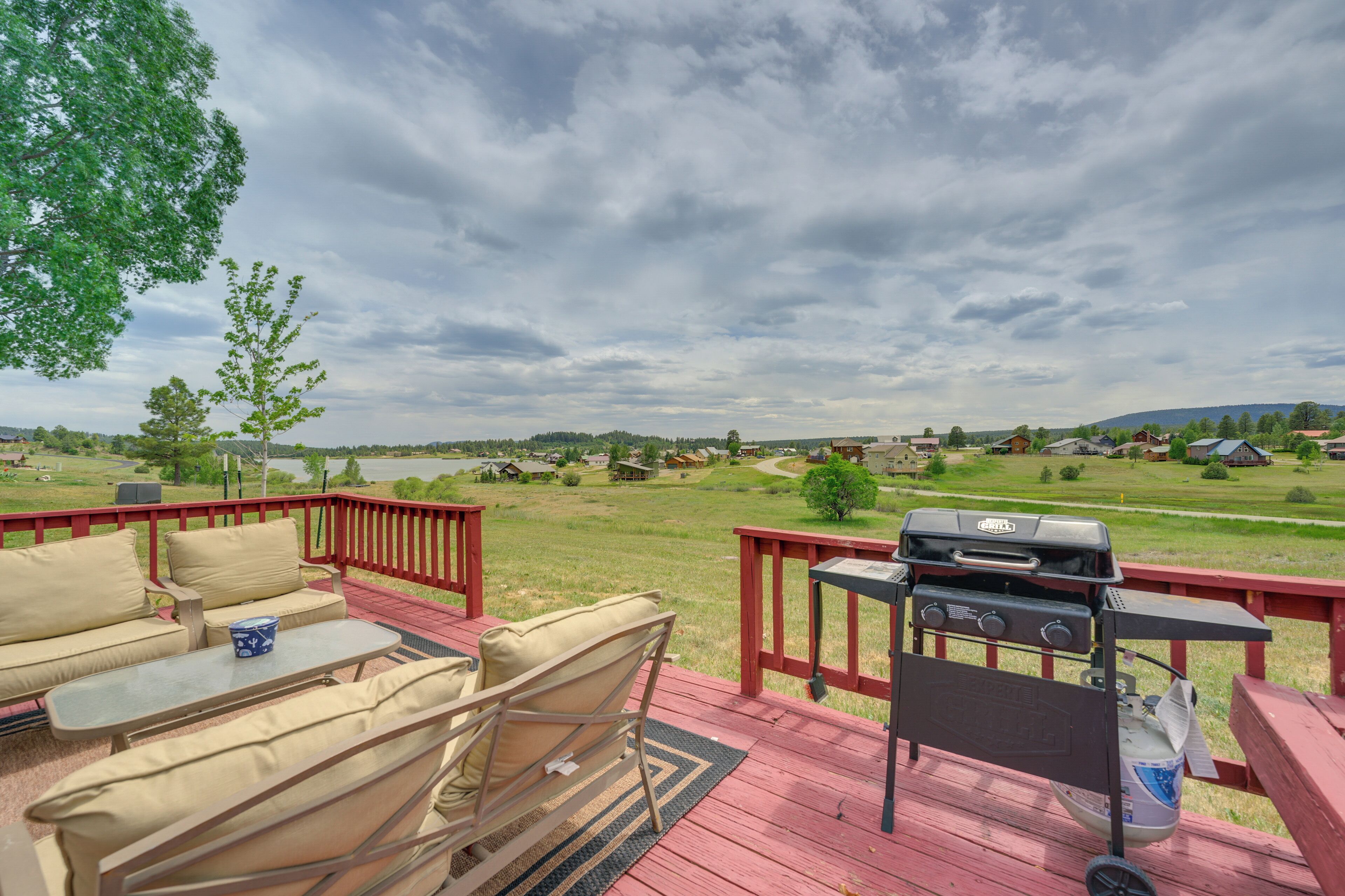 Une terrasse dotée de mobilier d’extérieur, d’un barbecue et offrant une vue sur un lac et des maisons.