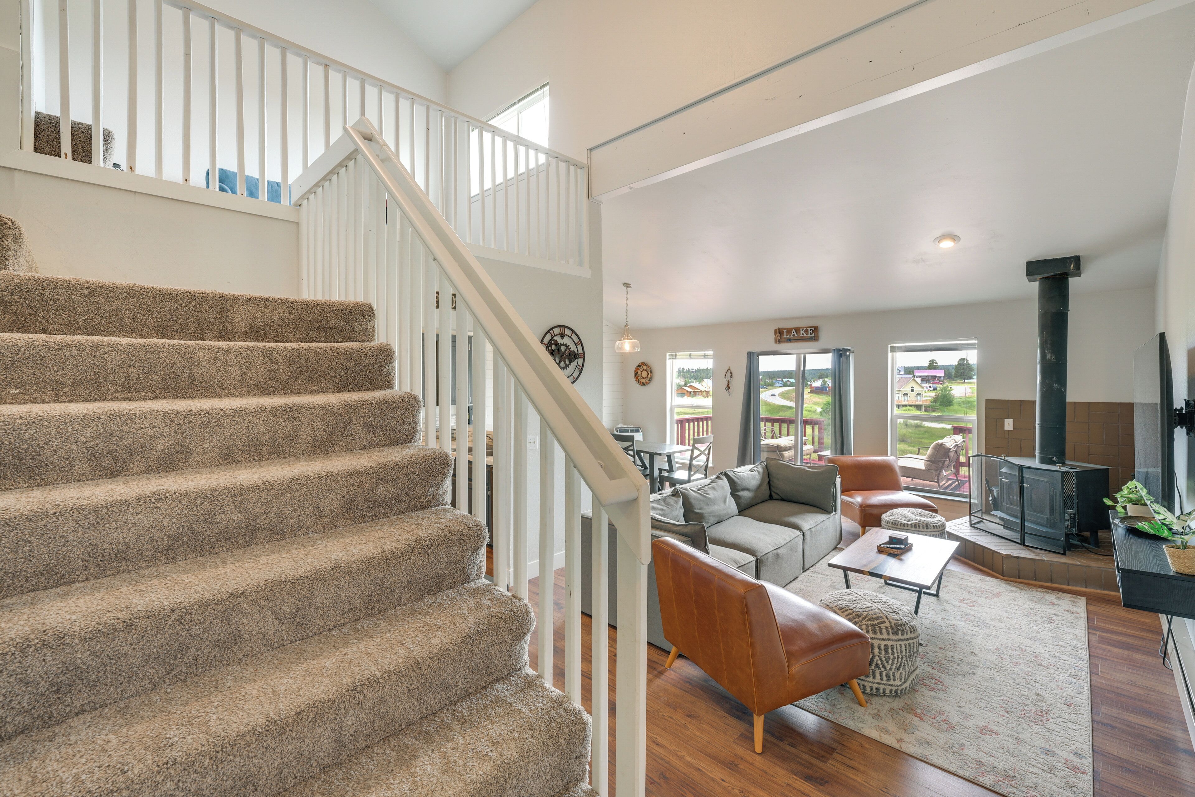 A spacious living area with a staircase, a fireplace, and a view of the outdoors.