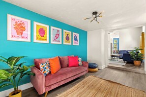 A living room with a teal wall, a red sofa, and four framed posters. - Private Pool! Family Getaway, 5 Mi to Seaworld (San Antonio)