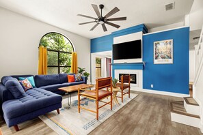 A living room with a sectional sofa, wooden chairs, a TV, and a fireplace. - Private Pool! Family Getaway, 5 Mi to Seaworld (San Antonio)