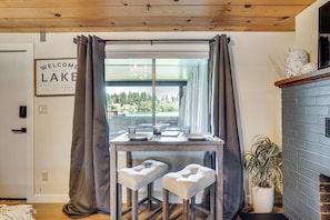 A dining area with a table, two cushioned stools, a potted plant, and a fireplace.