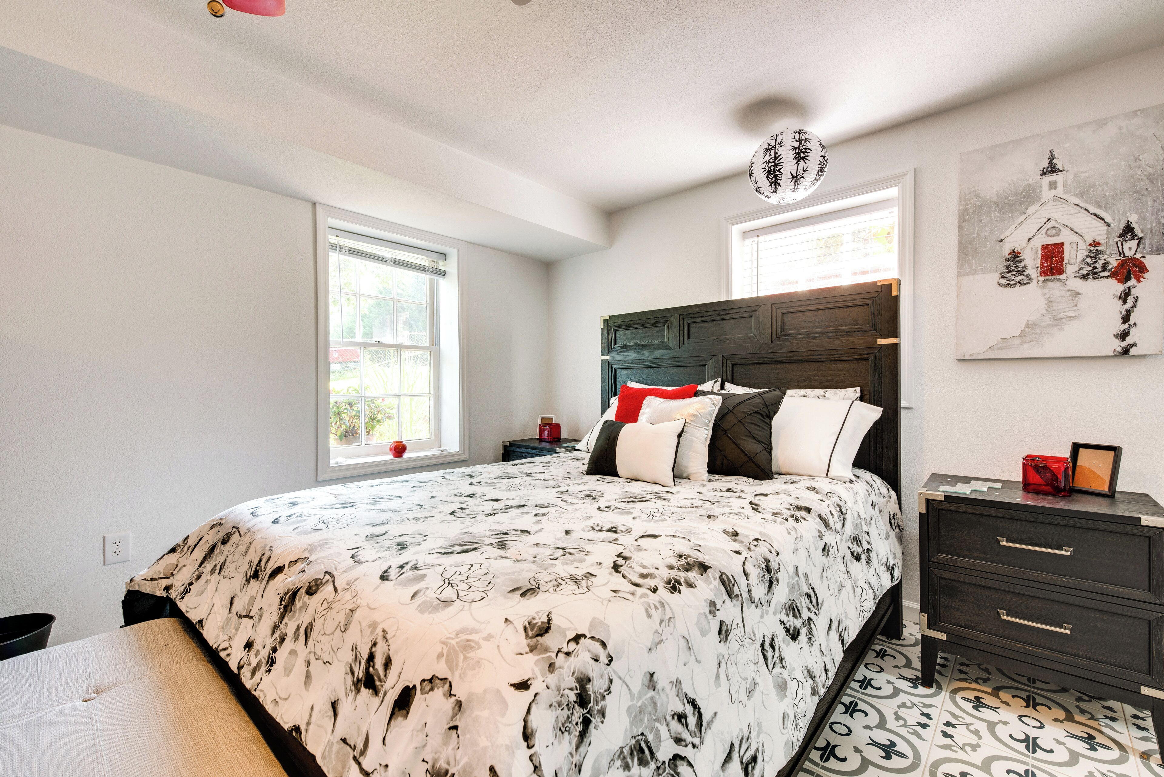 A bedroom with a large bed, a nightstand, a dresser, and a window with blinds.