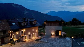 Une maison à deux étages dotée de panneaux solaires, d’une façade en pierre et offrant une vue sur les montagnes.